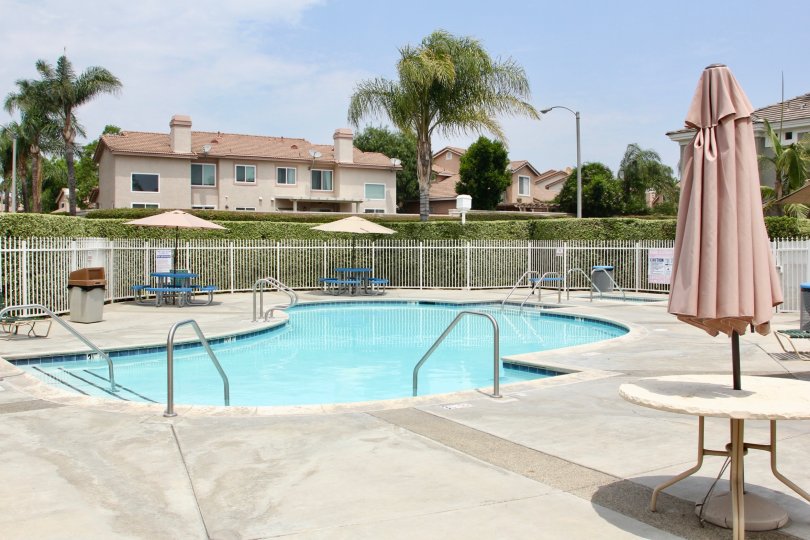 there is a large swimming pool at the front of house with table and chair is surrounded by trees and grasses