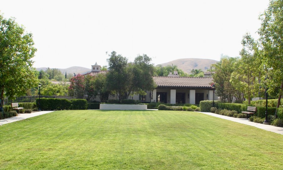 there is a beautiful garden located with full of trees and grasses surrounding the house and there is a mountain at the back of the house