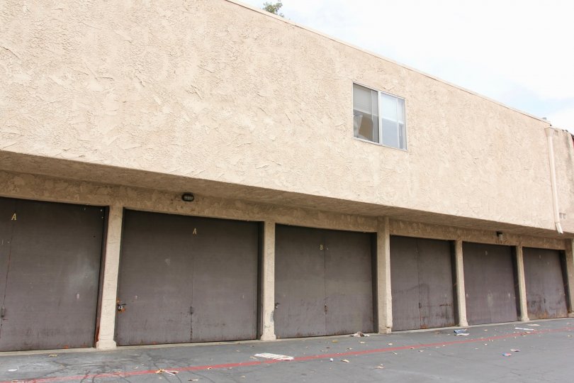 Rectangular apartment building with single window and brown garage doors