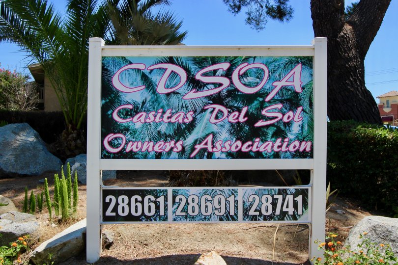 A mural of palm tree sits behind lettering on a sign in Casitas Del Sol community.