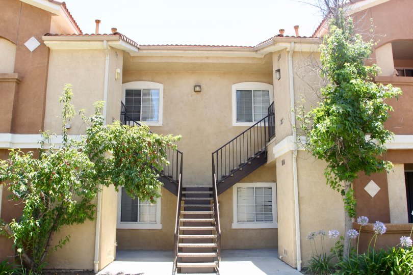 house contains stair case at the front and surrounded by full of trees and grasses