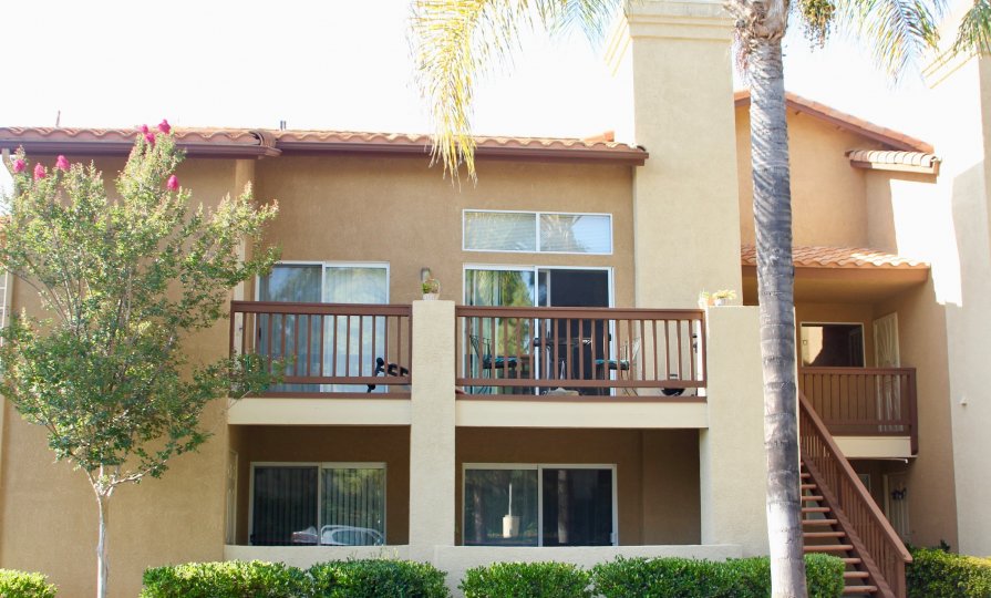 Double story condo with balconies and trees with shrubs and palm trees