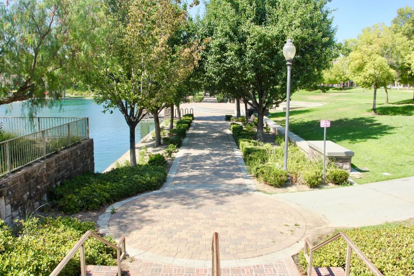 Trees line either side of a brick path near a pond at Savannah at Harveston.