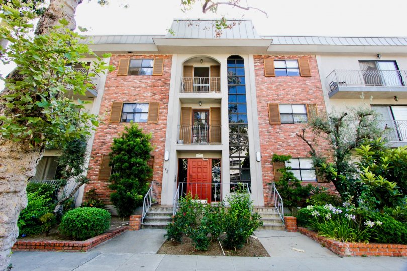 A red brick house at 152 S Oakhurst Dr with two balconies and multiple plants