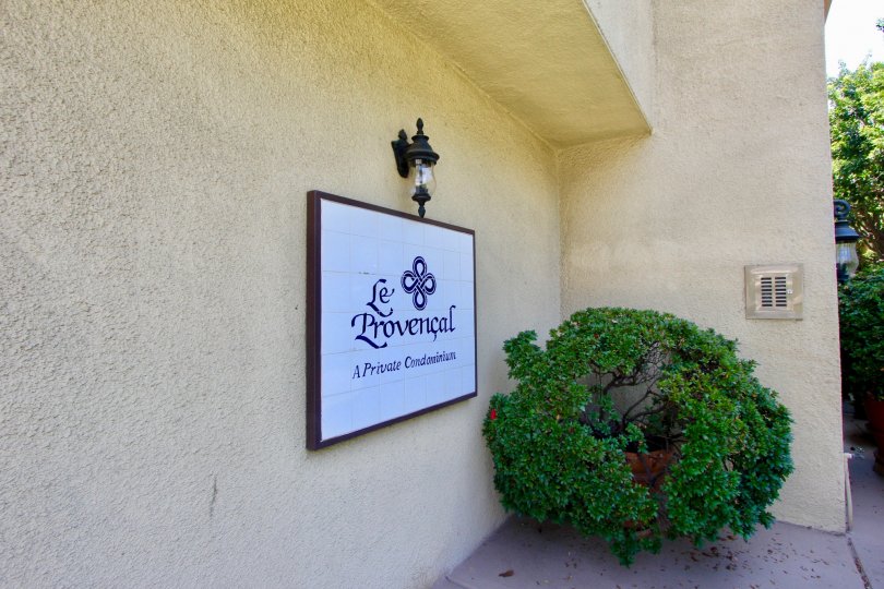 A beige-colored building with stucco walls and a green bush in Le Provencal