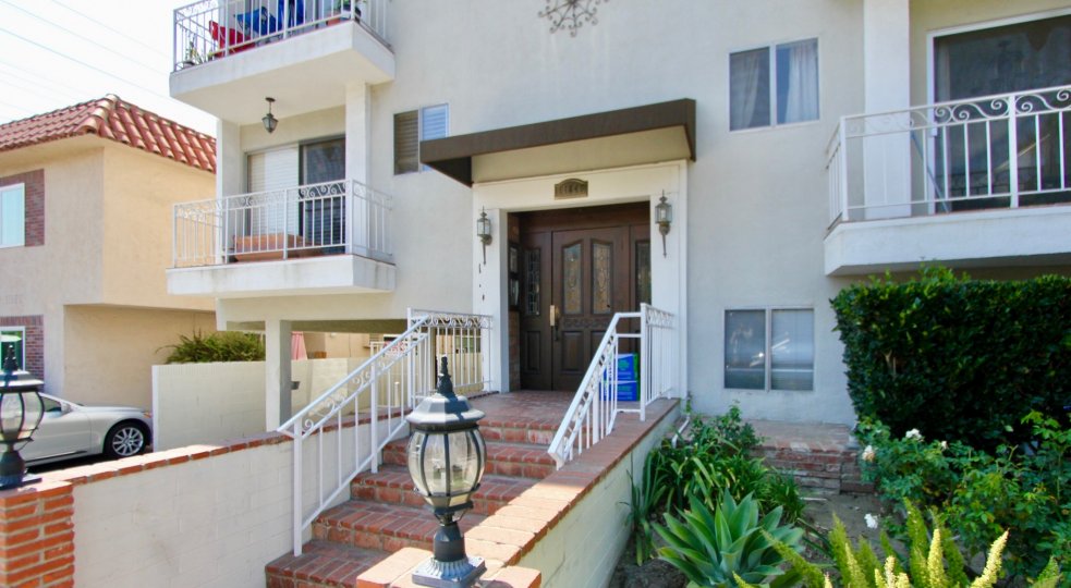 Front entrance at Manor House with big wooden door with brick stairs and white railings.
