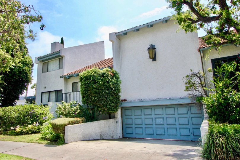 The front of a 1144 17th St building with a garage and bushes on a sunny day.