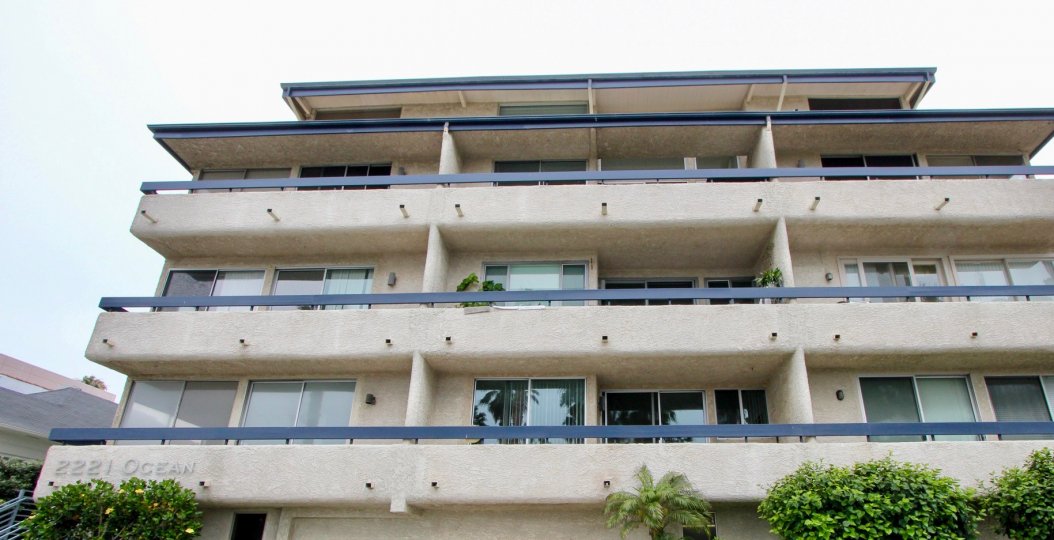A tan building at 2221 Ocean with three balconies and a black guard rail