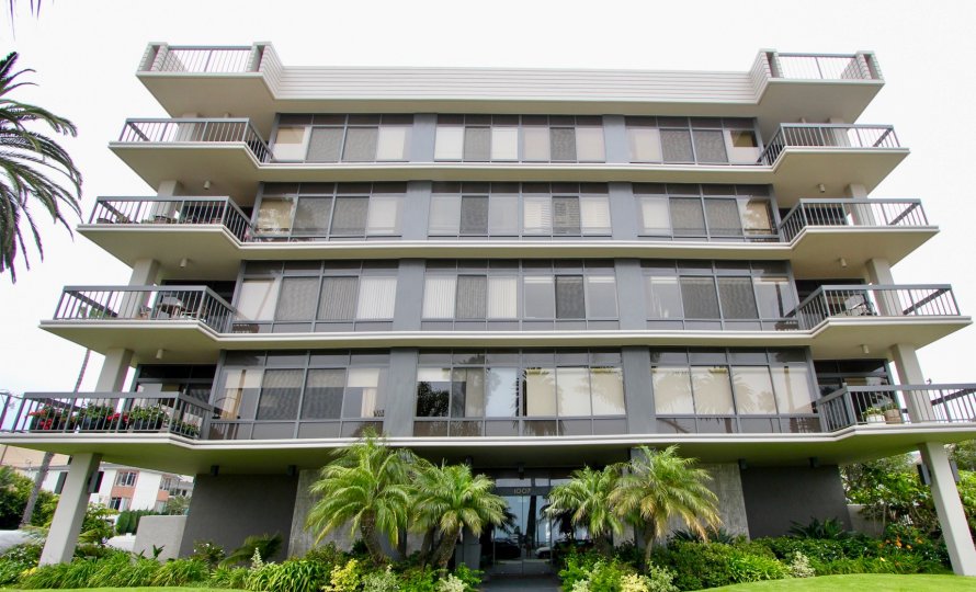Large Boca Monica building with palm threes and bushes on a cloudy day.