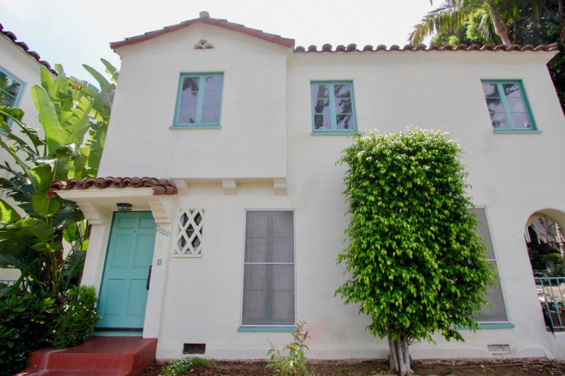 Two story house painted white with aqua trim. Red tile roofing and Spanish style details give it a Spanish look.