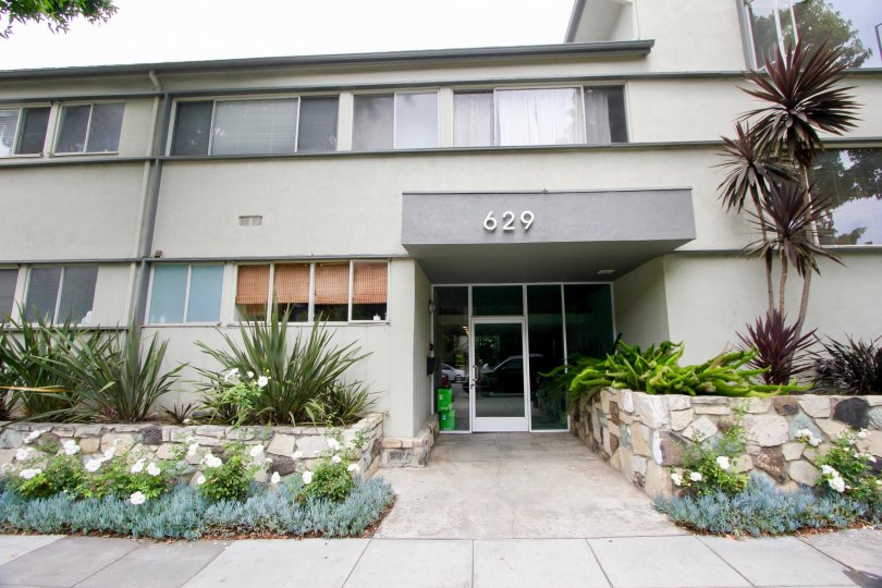 A grey colored house with number 629 and glass windows and doors. Fancy grass and bushes on front.