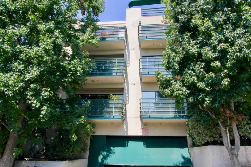 A white building in the Vista Larrabee neighborhood with tall trees and six balconies
