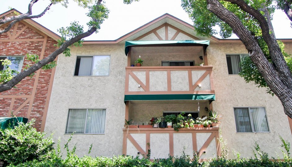Criss Cross Applesauce house with brick and tree lined shrubbery with balconies and potted plants