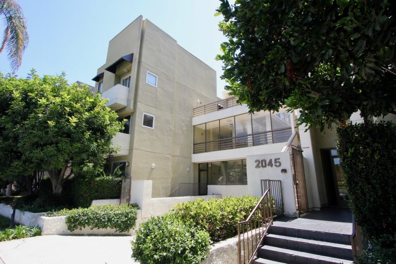 Shade and palm trees planted at the Cream colored apartment building at the Pines in West LA California
