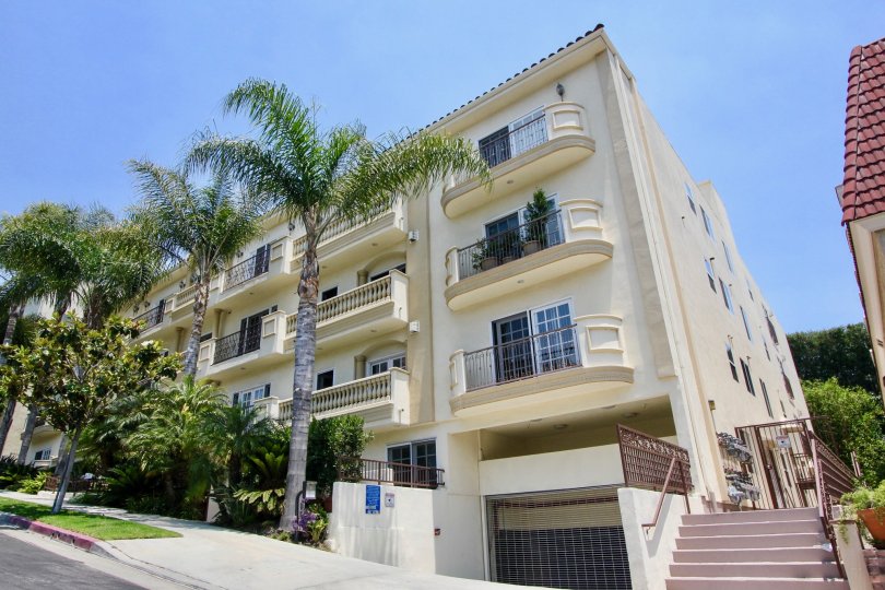 A street view of Century Fox Hills, and cream residential building on a slanted street with indoor parking.