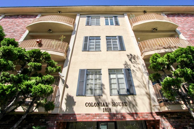 Colonial house building have three floor with balcony and flower pots, tree.