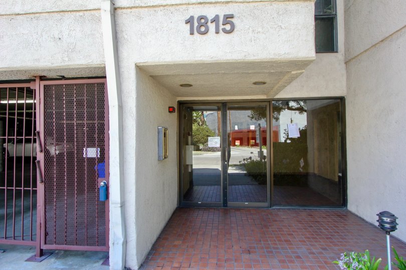A white building in the Glendon Villas community with a glass front door and red gate
