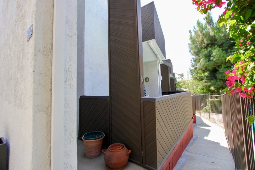 A white building in the Village Townhouses neighborhood with brown fences and pottery