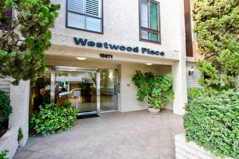 The Westwood Place, with multiple green plants and shrubs in front of it and a large glass door