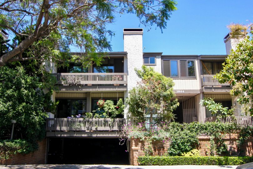 A sunny day in Woodvale Village with an attached house with an undergound garage surrounded by trees