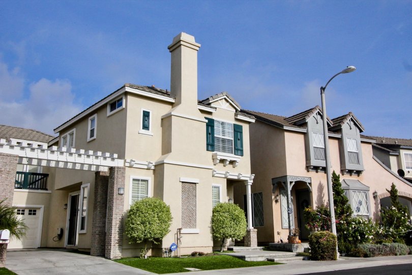 Townhomes with landscaping and clouds in sky above.