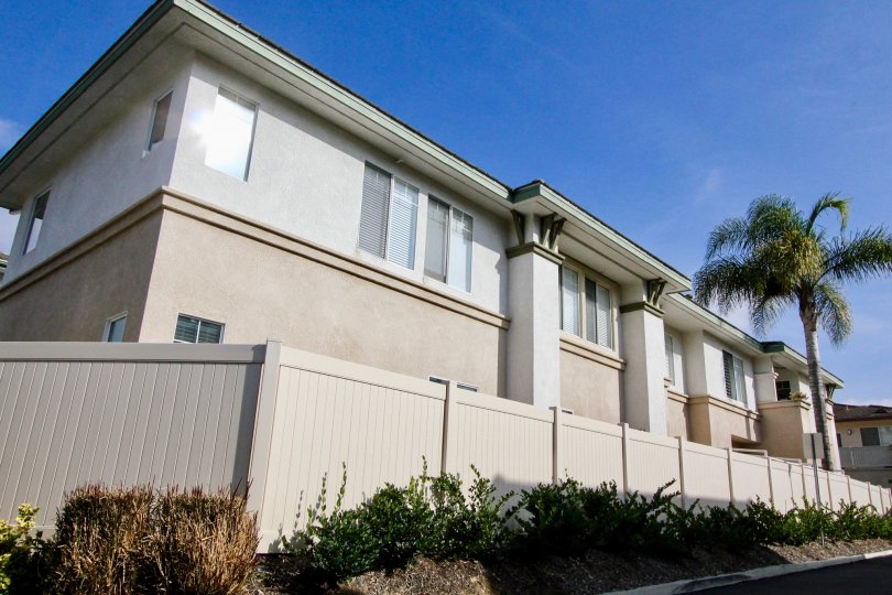 Building with sa sunny sky and a fence and a tree in the Orleans Community in Aliso Vieja, CA.