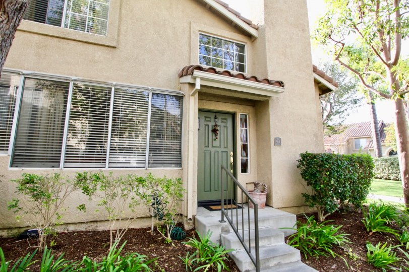 A NICE HOUSE WITH LIGHT YELLOW COLOR WITH INFRONT OF STEPS WITH NICE WINDOWS
