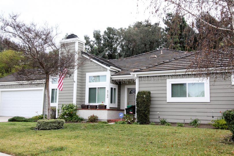 THIS IMAGE VIEWS THE FRONT OF THE HOUSE THAT HAS THE DOOR NUMBER ON THE WALL, SHOWS GLASS WINDOWS, BEAUTIFUL LAWN, TREES, PLANTS IN THE CROWN POINTE