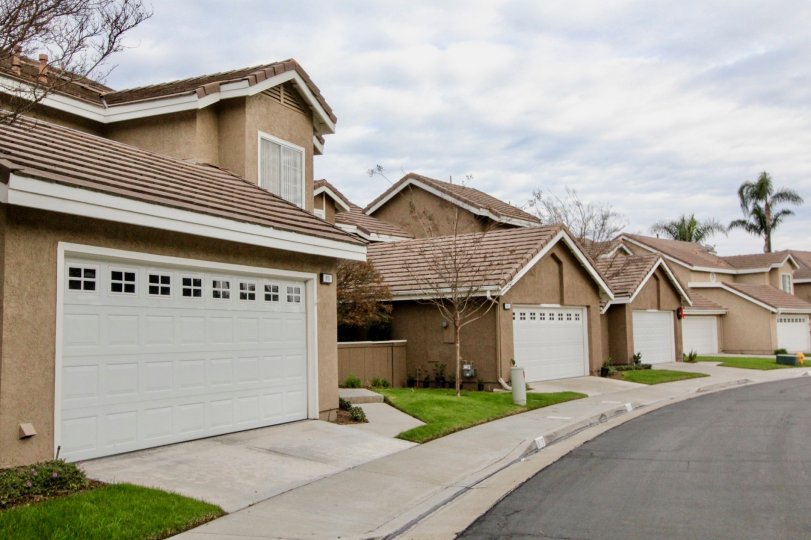 line of houses with garage doors in front and a pathwalk with grass in middle