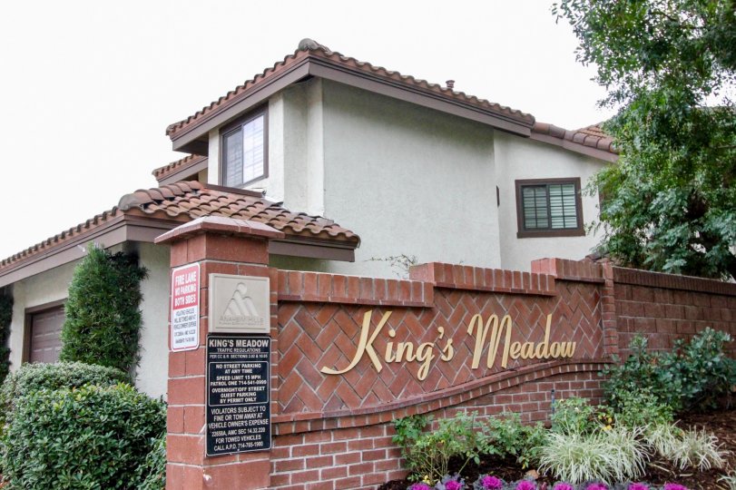 A large pink brick wall with gold writing near homes inside Kings Meadow in Anaheim Hills CA