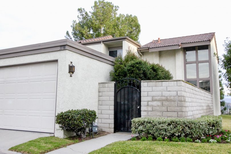 a house entrance with a black door a garage on side and grass with bushes around