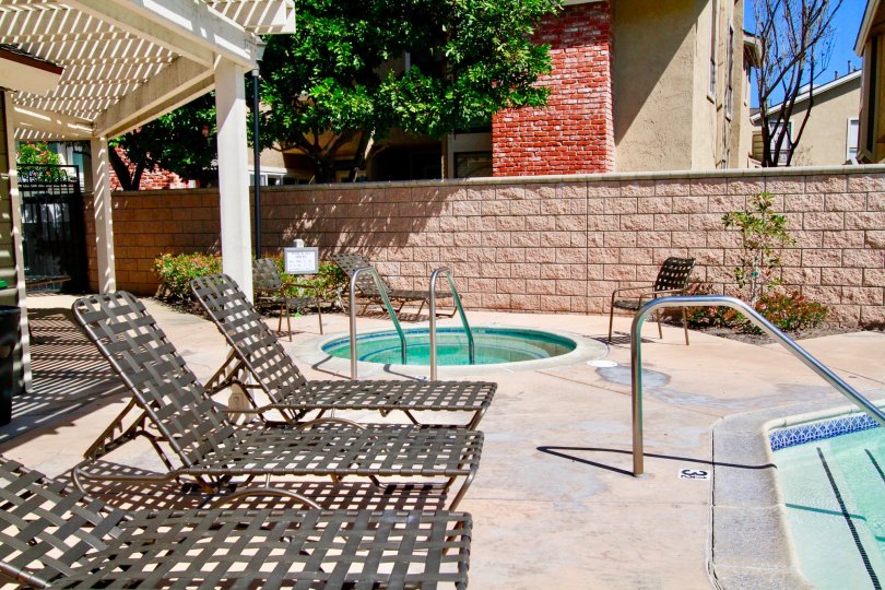 A SMALL KID POOL WITH TWO SITTING CHAIRS AND A ROOF NEAR TO THE PLACE AND SOME TREES ALSO AVALIABLE AT THE MORNING TIME.