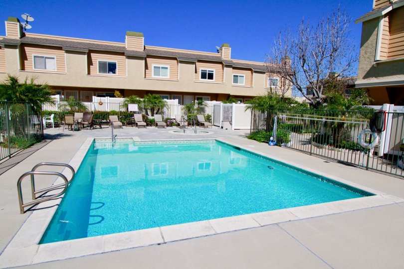 A large blue rectangle pool surrounded by a black iron fence at ocean Breeze Villas in Costa Mesa CA