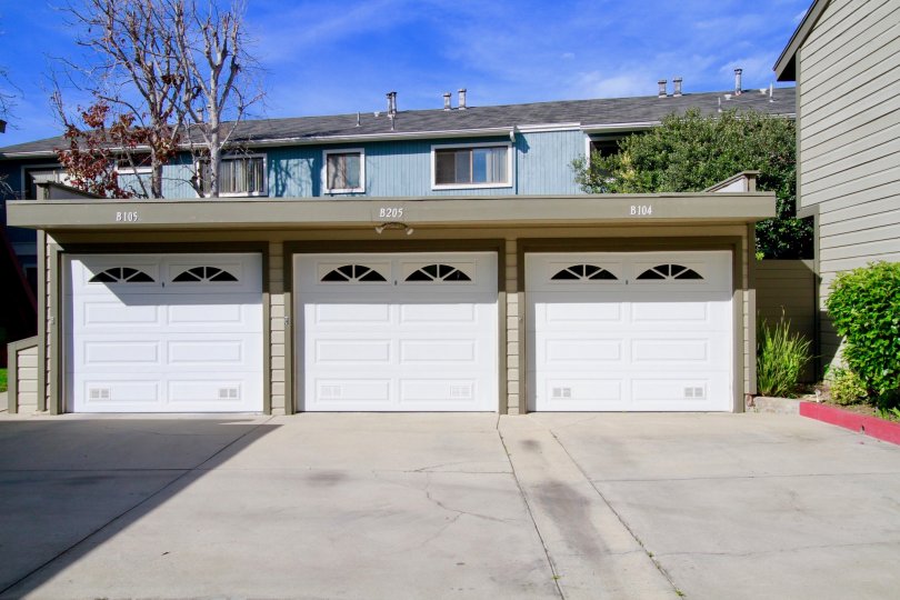 A three car garage with house or apartment complex in the background