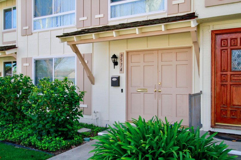 A DOOR CLOSED AND THE BUILDING LOOKS LIKE MEDIUM SIZE BUNGALOW AND BALCONY ALSO AT THE FIRST FLOOR AND SMALL PLANTS ALSO NEAR TO THERE AT THE MORNING TIME