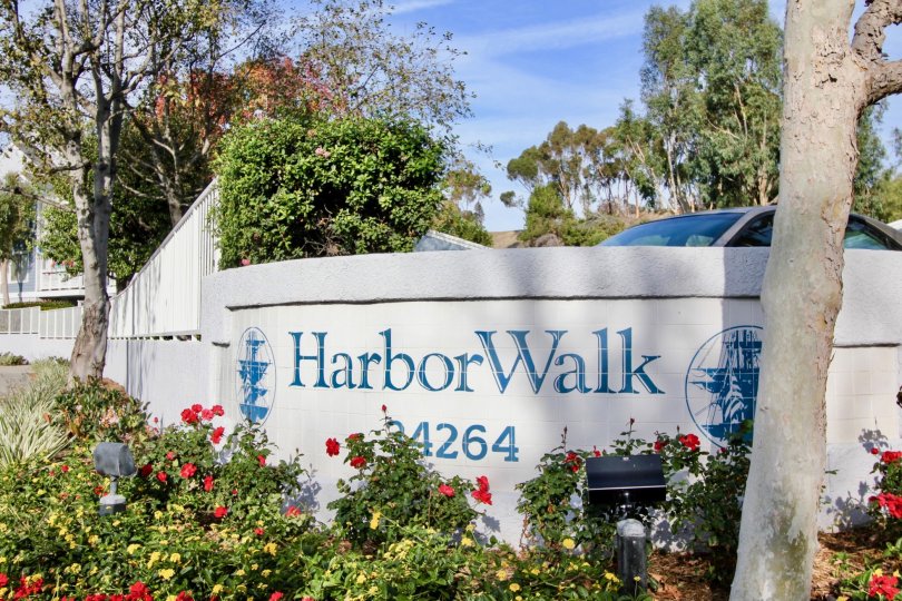 A sunny day in the Harbor Walk with a sign on the wall and car.