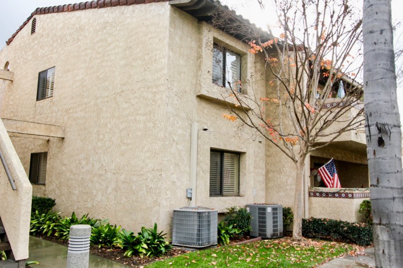 Dark tan housing with projected window areas outside with some plants and trees located in Fountain Crest community.