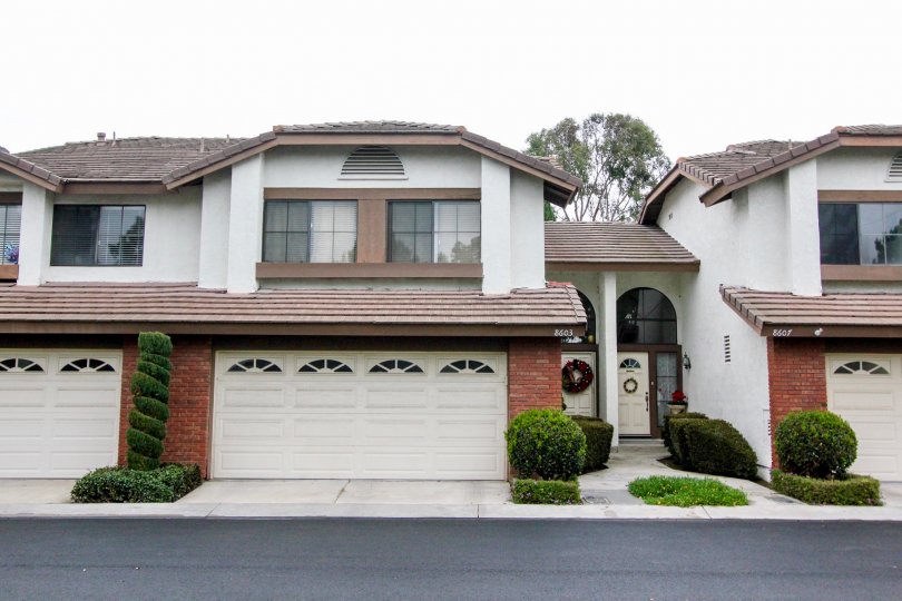 A long paved road sits in front of a two story home with two garages in Shadow Lane in Fountain Valley CA