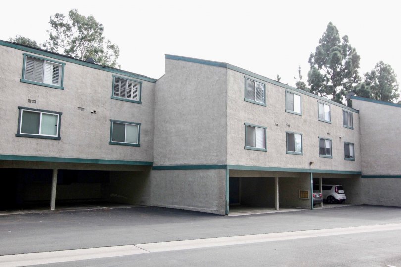 Gray apartment building in Brea Country with parking spaces and green trim.