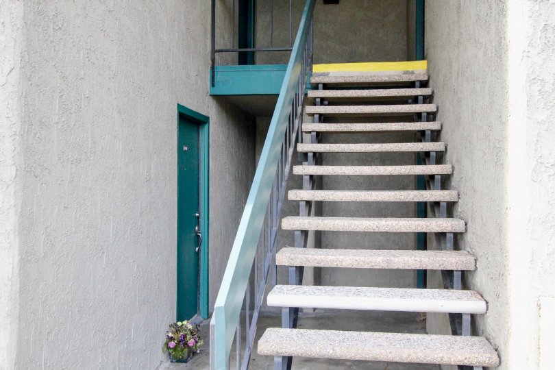 Gray stucco open stairwell leads to turquoise doors in Brea Country community of Fullerton, CA.