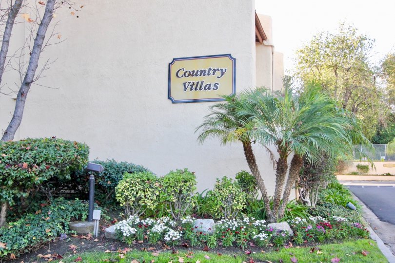 A sign for the Country Villas community with assorted plants in a garden.