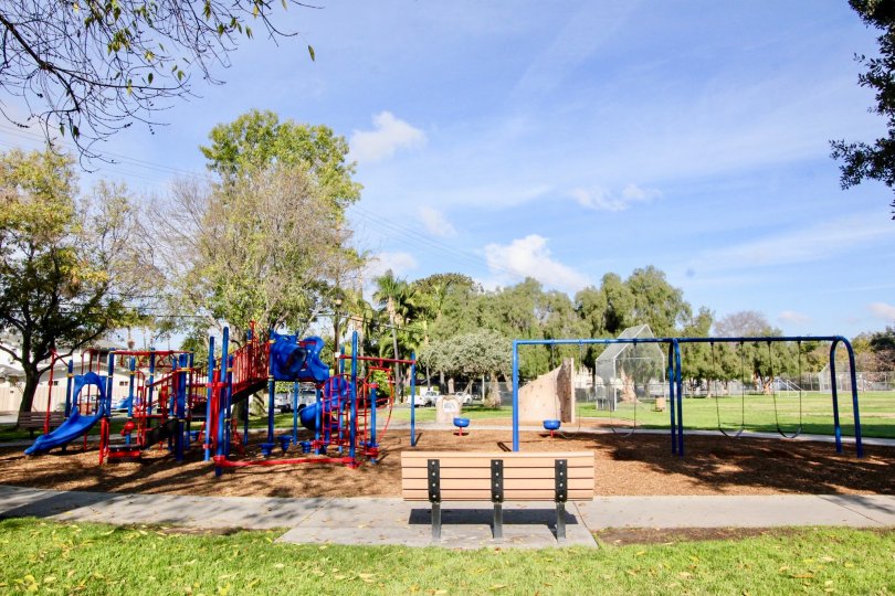 Park in Fullerton Fountains with a bench and a playground on a sunny day.