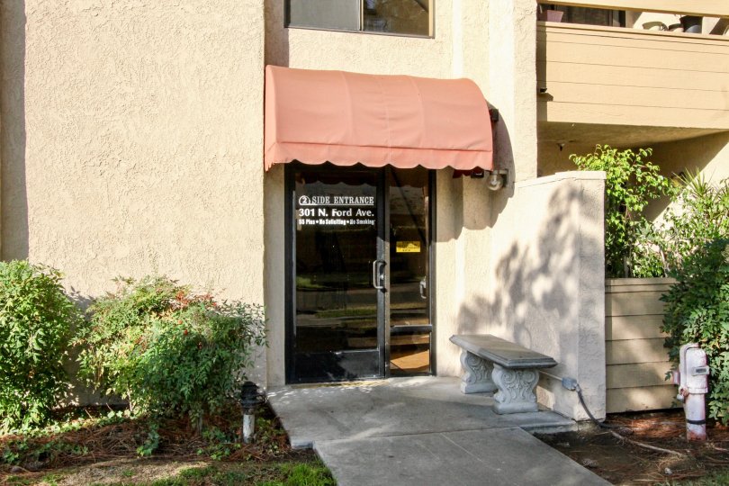 Address are painted in glass door of villa in Fullerton Fountains with bench and bushes