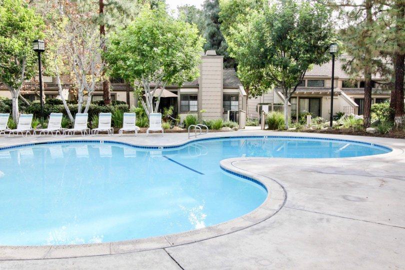 The pool in the Hidden Lakes community with deck chairs and lamps.
