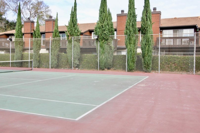 Tennis courts in the Mark III Townhomes with a metal fence on a cloudy day.