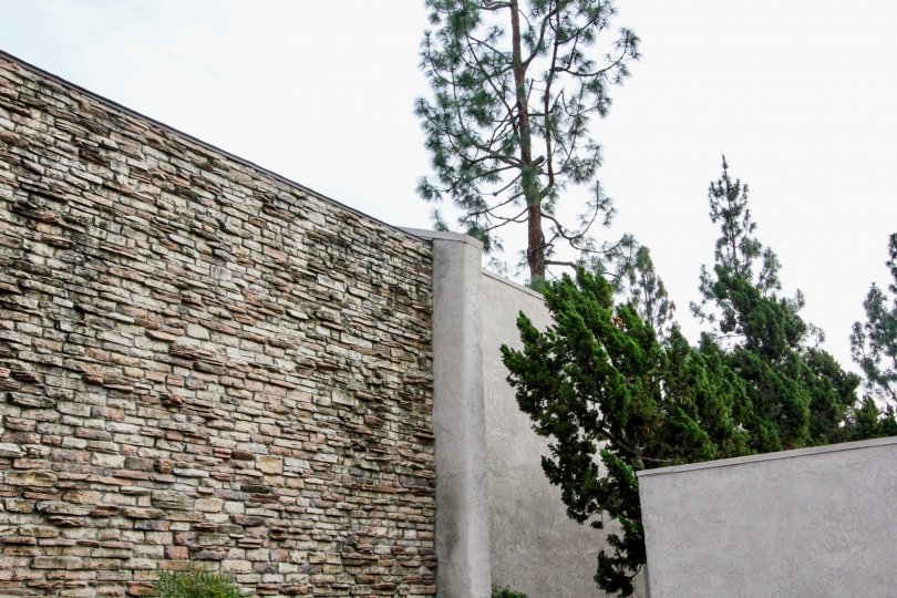 A stone fence in Park Ridge with trees on a cloudy day.