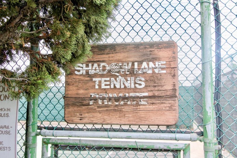 A wooden sign sits against a metal fence at Shadow Lane in Fullerton CA