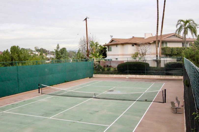 Tennis Court in Shadow Lane with a net and bench on a cloudy day.