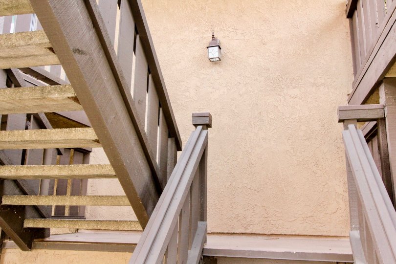 The stairs in villa at Via Valencia is made up of wood and gap between each stairs is wide with light lamps is present at wall