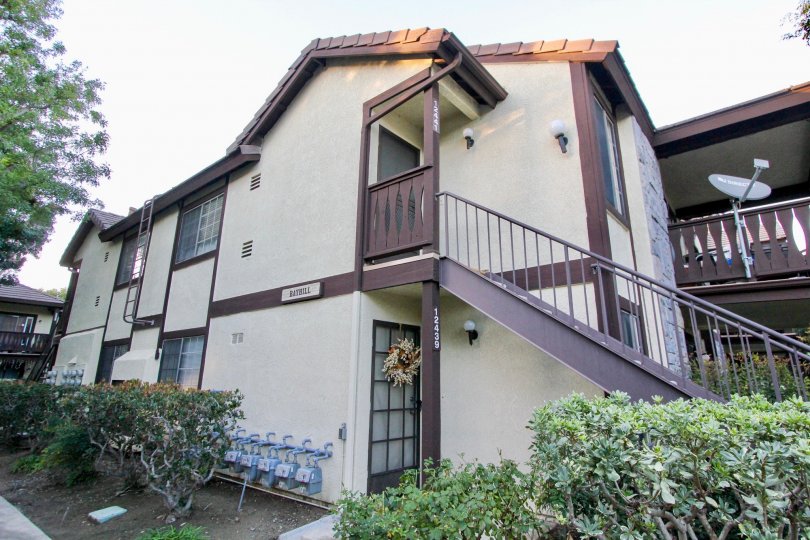 THIS IMAGE VIEWS THE VILLAS THAT HAS SURROUNDED BY THE PLANTS, TREES AND SHOWS THE DISH, NUMBER AND NAME BOARD ON THE WALL IN THE CITY OF GARDEN GROVE